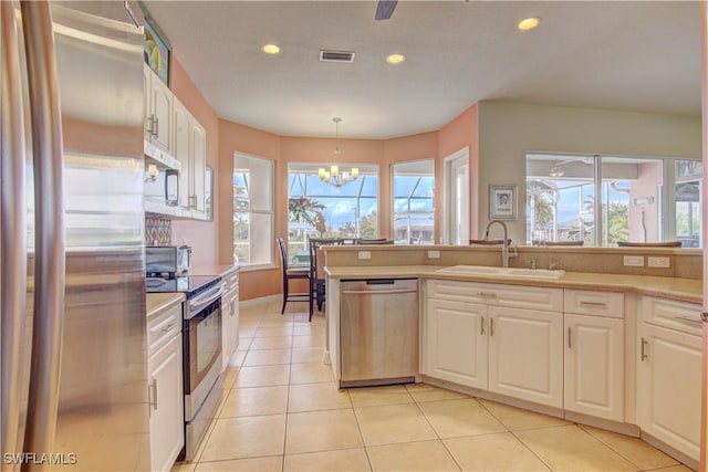 kitchen with appliances with stainless steel finishes, decorative light fixtures, white cabinetry, sink, and a notable chandelier