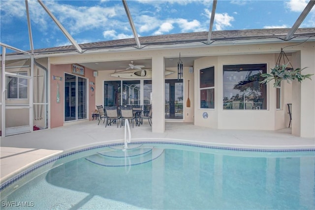 view of pool with a patio, ceiling fan, and glass enclosure