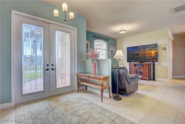 foyer entrance with a notable chandelier, french doors, and light tile patterned flooring