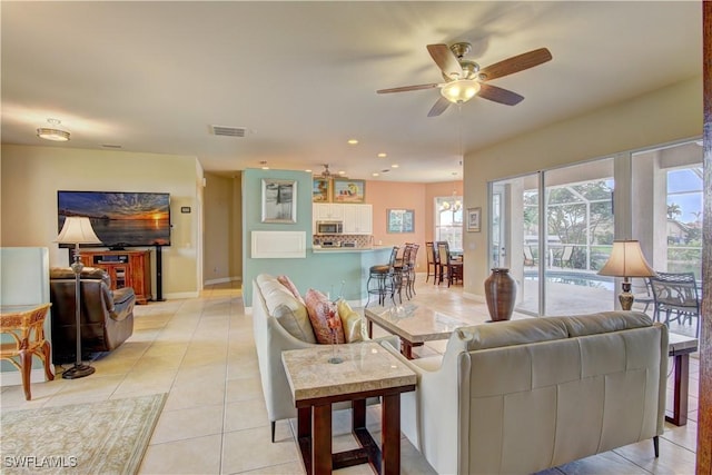 tiled living room featuring ceiling fan with notable chandelier