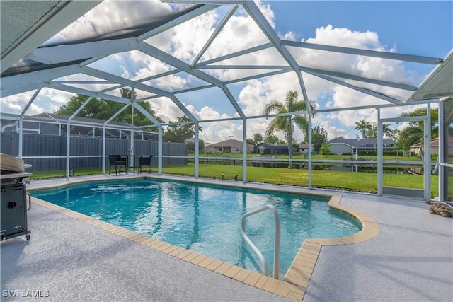 view of swimming pool featuring a yard, a patio, and a lanai