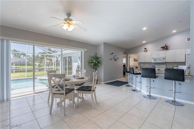 dining area with ceiling fan, light tile patterned floors, and lofted ceiling