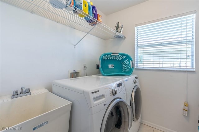 laundry room with light tile patterned flooring, separate washer and dryer, and sink