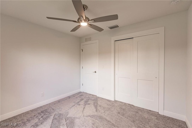 unfurnished bedroom featuring ceiling fan, a closet, and light carpet