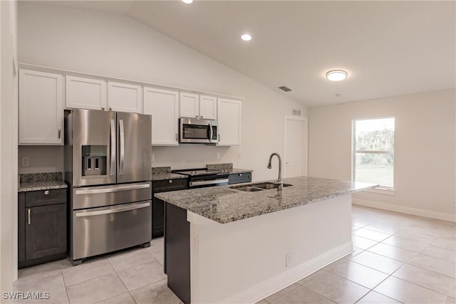 kitchen with light stone countertops, appliances with stainless steel finishes, a kitchen island with sink, sink, and white cabinetry