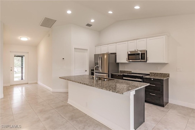 kitchen with white cabinets, stainless steel appliances, vaulted ceiling, and a kitchen island with sink