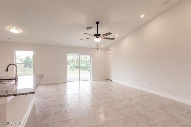 tiled spare room featuring vaulted ceiling, ceiling fan, and sink