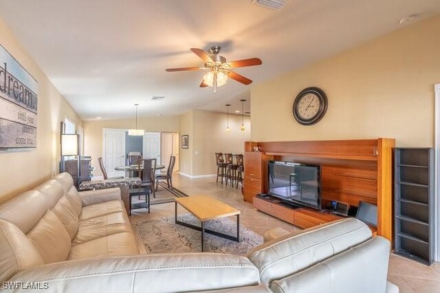 tiled living room with ceiling fan and vaulted ceiling