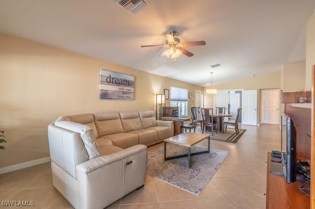 tiled living room featuring ceiling fan and vaulted ceiling