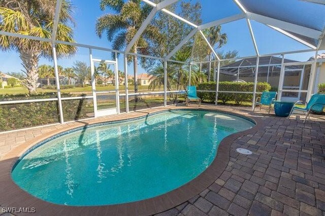 view of pool featuring glass enclosure and a patio