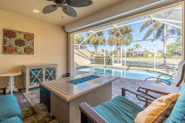 exterior space featuring glass enclosure, ceiling fan, and a patio