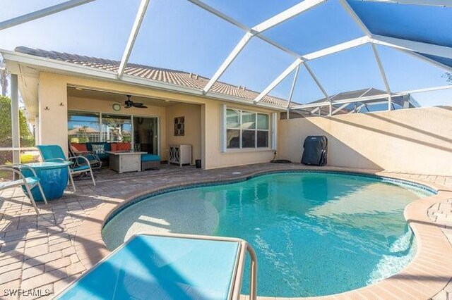 view of swimming pool featuring a lanai, a patio area, and ceiling fan