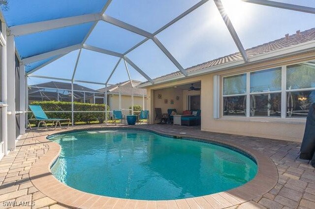 view of pool featuring glass enclosure, ceiling fan, and a patio