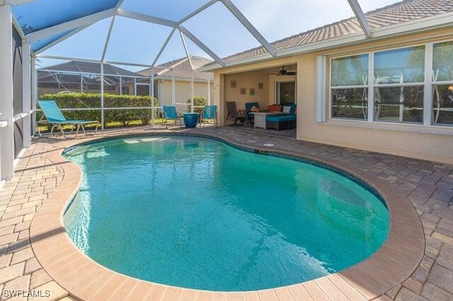 view of swimming pool with ceiling fan, a lanai, and a patio