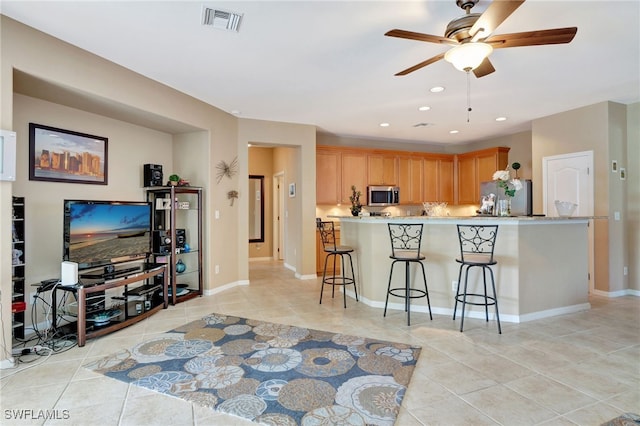 kitchen featuring a breakfast bar, light tile patterned floors, ceiling fan, kitchen peninsula, and stainless steel appliances