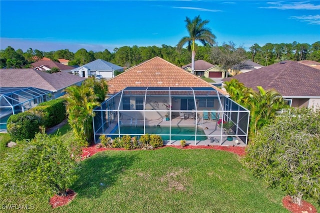 rear view of house with a yard, glass enclosure, and a patio area