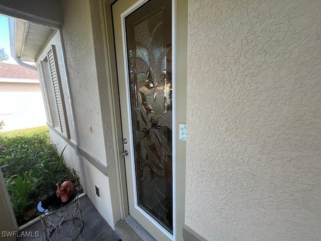 8040 Liriope Loop, Lehigh Acres, FL 33972 - doorway to property with stucco siding
