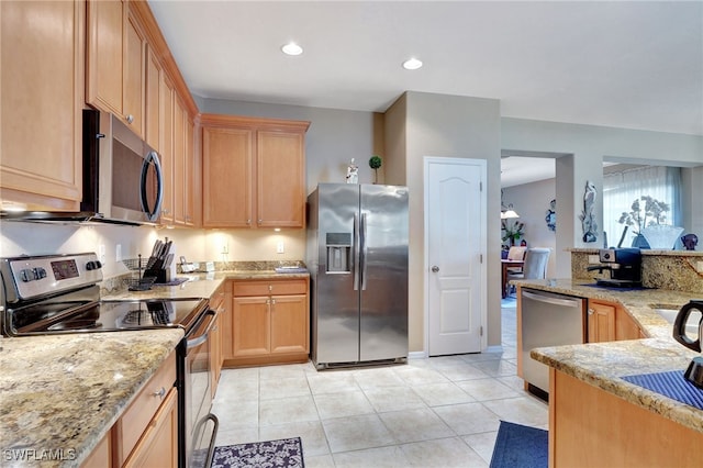 kitchen featuring light tile patterned flooring, stainless steel appliances, light stone counters, and light brown cabinets