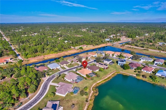 drone / aerial view featuring a residential view, a wooded view, and a water view