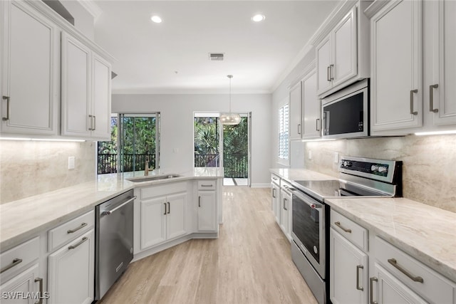 kitchen with decorative light fixtures, sink, white cabinetry, and stainless steel appliances