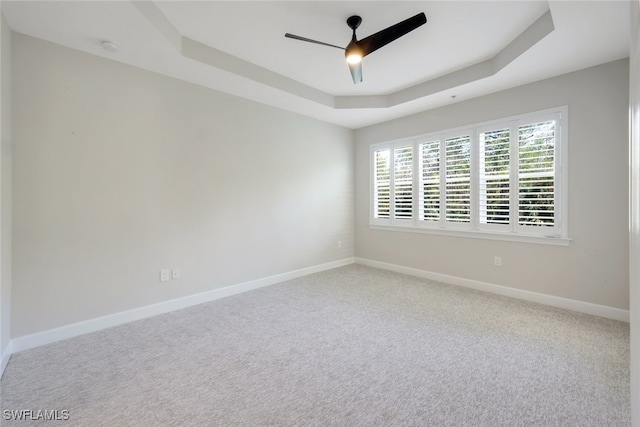 spare room featuring carpet floors, a raised ceiling, and ceiling fan