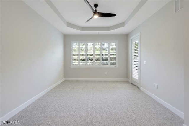 unfurnished room featuring ceiling fan, light colored carpet, and a tray ceiling