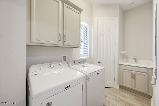 laundry area with sink, light hardwood / wood-style flooring, cabinets, and independent washer and dryer