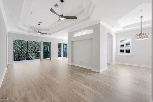 unfurnished living room with a raised ceiling, ceiling fan, a healthy amount of sunlight, and ornamental molding