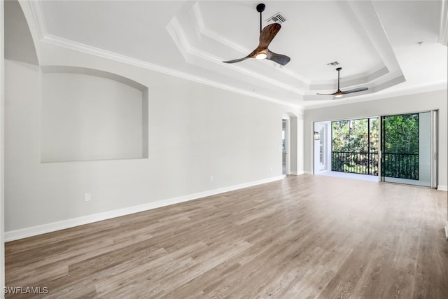 unfurnished living room with a tray ceiling, ceiling fan, wood-type flooring, and ornamental molding