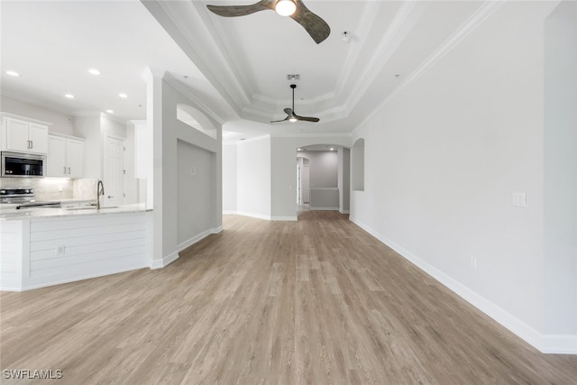 unfurnished living room featuring sink, ceiling fan, a raised ceiling, and crown molding