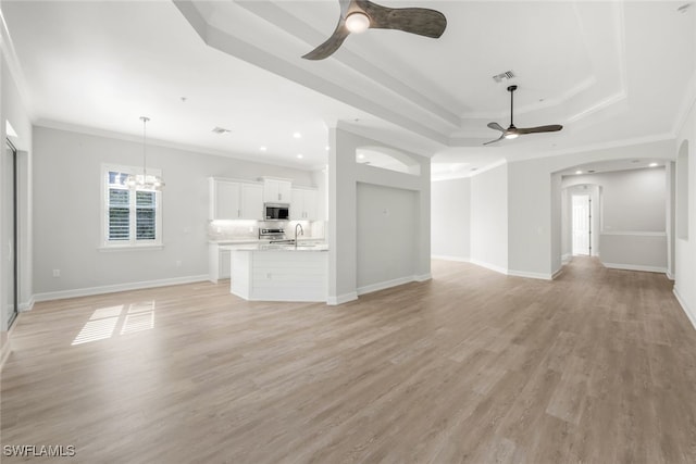 unfurnished living room with light hardwood / wood-style flooring, a raised ceiling, ornamental molding, and sink