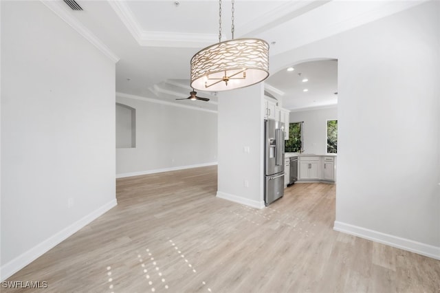 unfurnished dining area featuring ceiling fan, light wood-type flooring, crown molding, and a tray ceiling