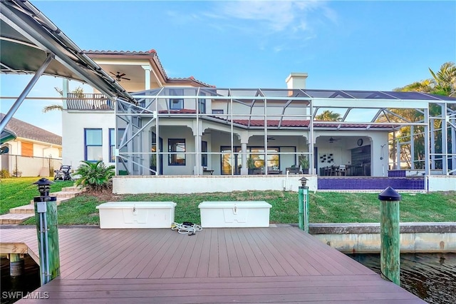 rear view of property with a yard, a lanai, and ceiling fan