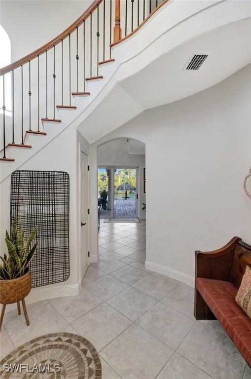 stairway featuring a towering ceiling and tile patterned flooring