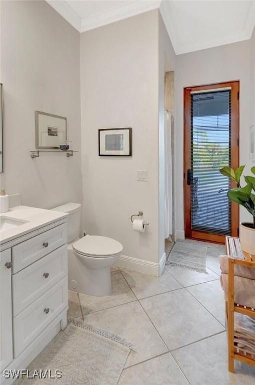 bathroom featuring tile patterned flooring, ornamental molding, vanity, walk in shower, and toilet