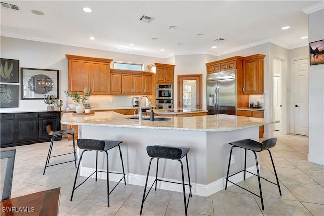 kitchen featuring sink, a breakfast bar area, stainless steel appliances, a large island, and light stone countertops