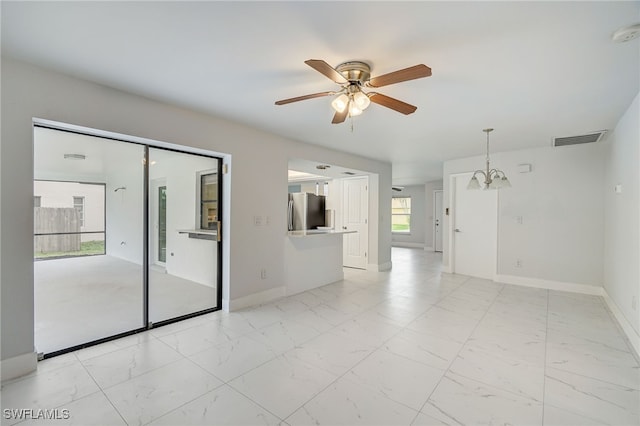 spare room featuring marble finish floor, baseboards, visible vents, and ceiling fan with notable chandelier