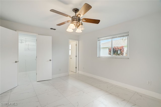 unfurnished room featuring marble finish floor, a ceiling fan, visible vents, and baseboards