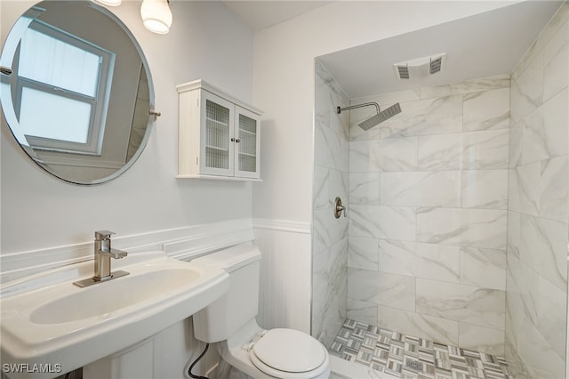 bathroom with toilet, a wainscoted wall, a sink, visible vents, and a shower stall