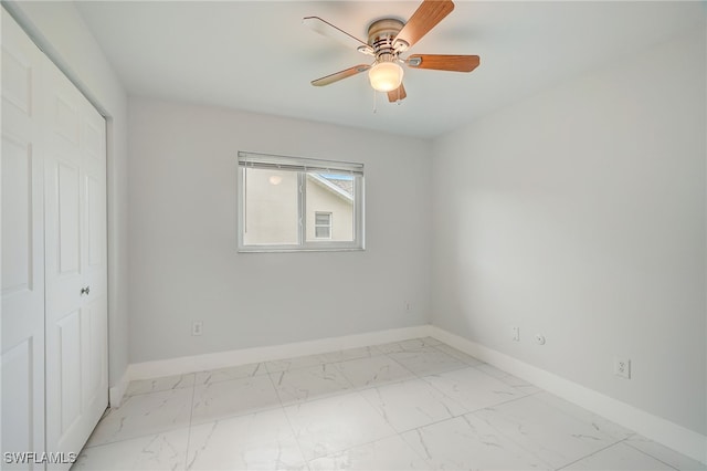 unfurnished bedroom with marble finish floor, baseboards, and a ceiling fan