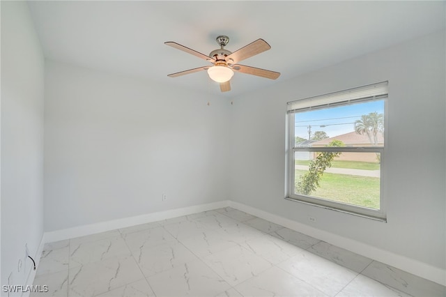 spare room featuring a ceiling fan, marble finish floor, and baseboards