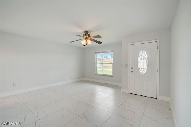 foyer entrance with marble finish floor, ceiling fan, and baseboards