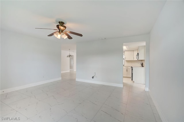 empty room featuring ceiling fan, marble finish floor, and baseboards