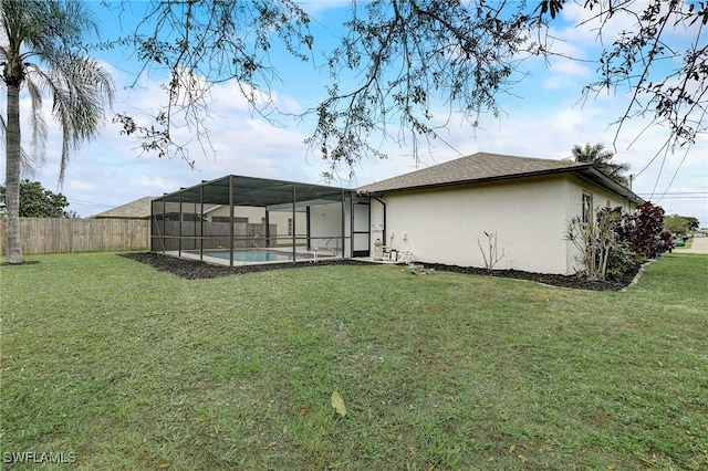 rear view of house with a lawn, fence, a fenced in pool, and stucco siding