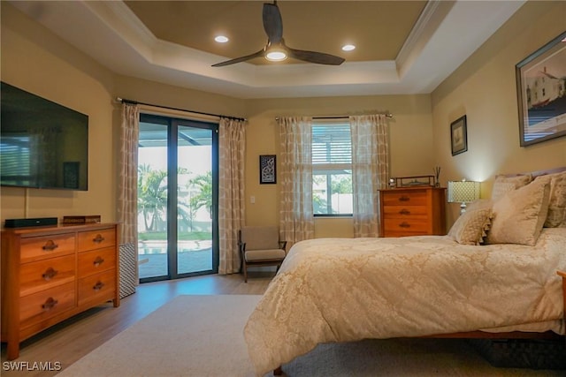 bedroom featuring a tray ceiling, access to exterior, and light wood-type flooring