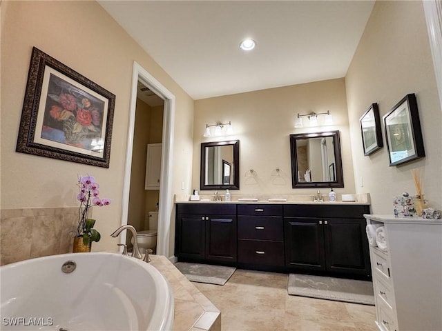 bathroom featuring vanity, toilet, and tiled tub