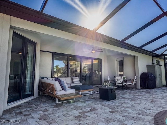 view of patio featuring an outdoor hangout area, glass enclosure, and ceiling fan