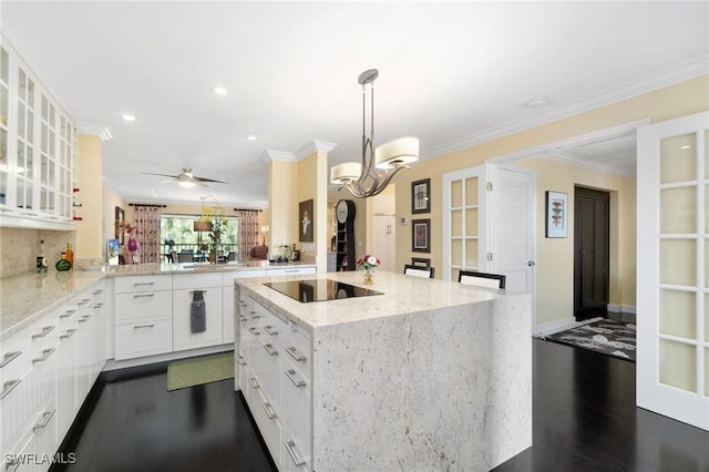 kitchen with a center island, kitchen peninsula, decorative light fixtures, black electric stovetop, and white cabinets