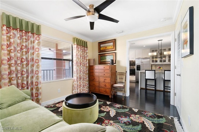 living room with ceiling fan with notable chandelier, dark wood-type flooring, and ornamental molding