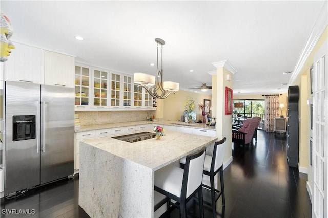 kitchen with hanging light fixtures, ceiling fan, light stone countertops, ornamental molding, and stainless steel fridge with ice dispenser